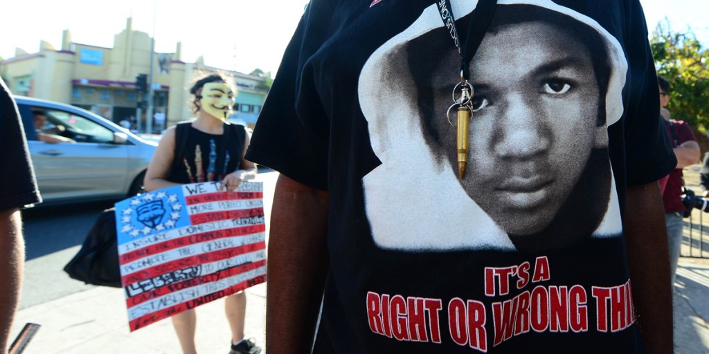 A man wears a single bullet around his neck over a T-shirt with the image of Trayvon Martin at a protest rally in Los Angeles.
