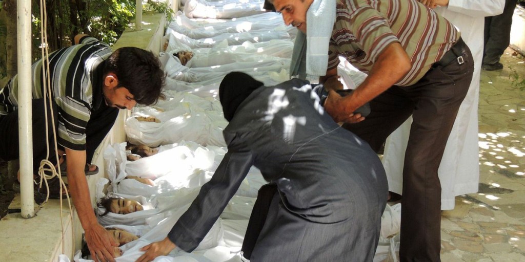 An unverified image released by the Syrian opposition's Shaam News Network shows a woman mourning over a body wrapped in shrouds laid out in a line on the ground with other victims which Syrian rebels claim were killed in a toxic gas attack by pro-government forces.