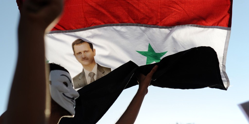 A protester waves a Syrian flag with the photograph of Syrian President Bashar al-Assad during a Turkish rally against a possible retaliatory attack on Syria.