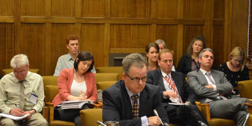 Craig Stevens (centre) appearing before the Upper House committee this morning.