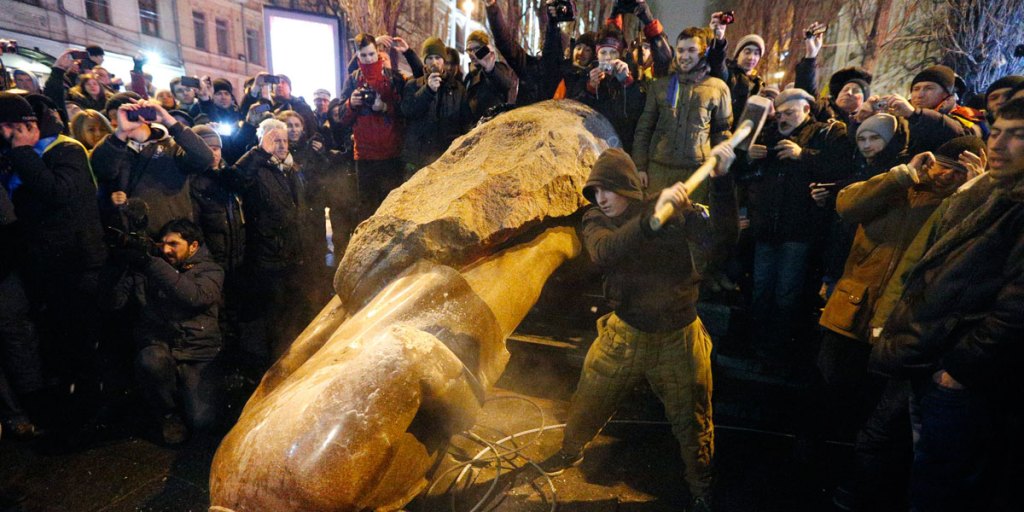 A protester hammers at a statue of former Soviet leader Vladimir Lenin as others gather around after it was toppled during a pro-European protest in downtown Kiev.