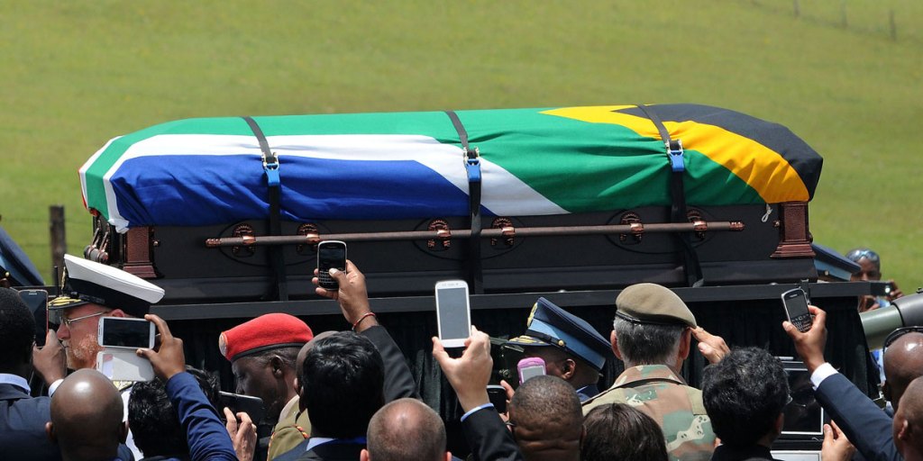 People take pictures as the coffin of South African former president Nelson Mandela is carried on a gun carrier for a traditional burial during his funeral in Qunu.
