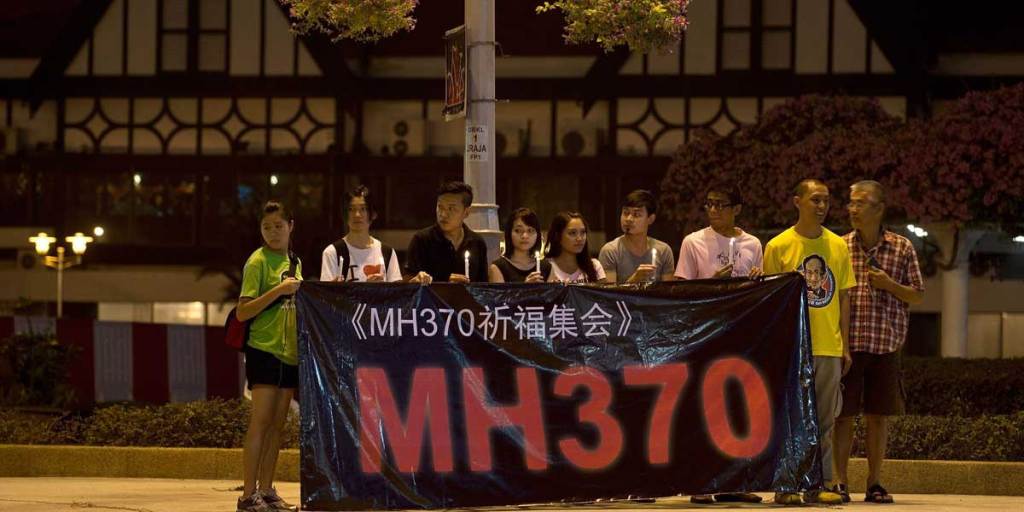 A group of Malaysians hold a banner and candles during a vigil for missing Malaysia Airlines passengers at the Independence Square in Kuala Lumpur.