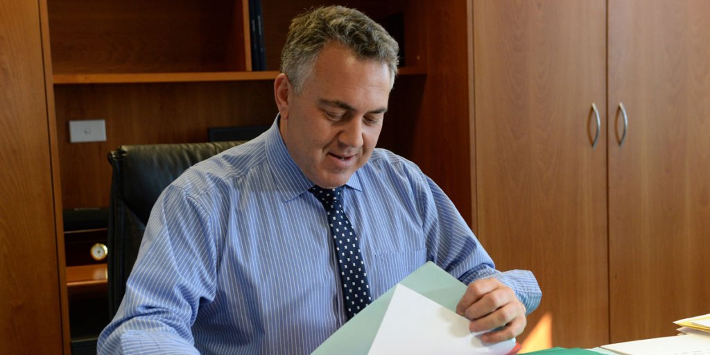 Joe Hockey looking through budget material at his desk.