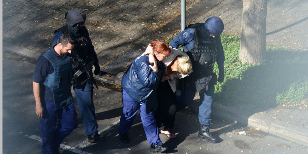 One of the traumatised hostages being led away by Police yesterday. AAP/Brenton Edwards