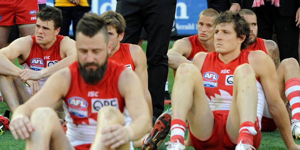 The Footballer-Formerly-Known-as-He-Who-Shall-Not-Be-Named (right) with other miserable Swans after the grand final.