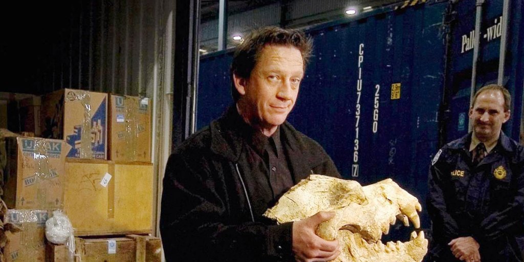 Professor Long with the fossilised skull of a hyena.
