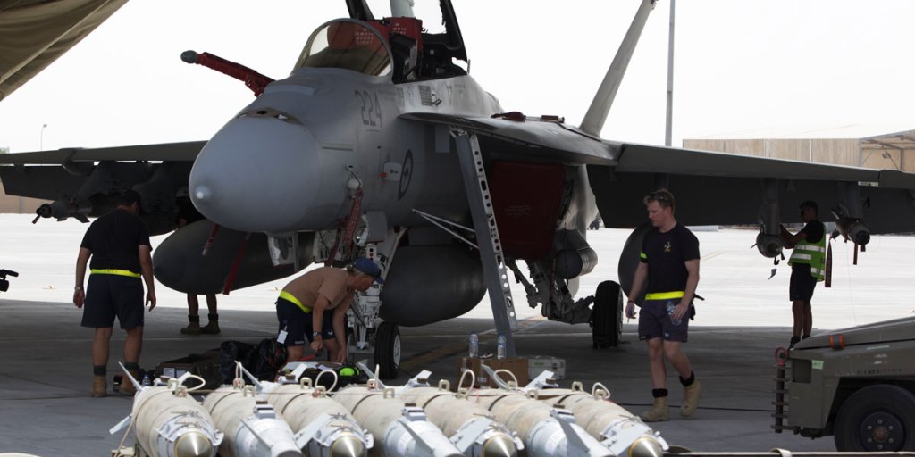 A team of Royal Australian Air Force Armament Technicians work around a RAAF F/A-18F Super Hornet to load explosive ordnance in the Middle East.
