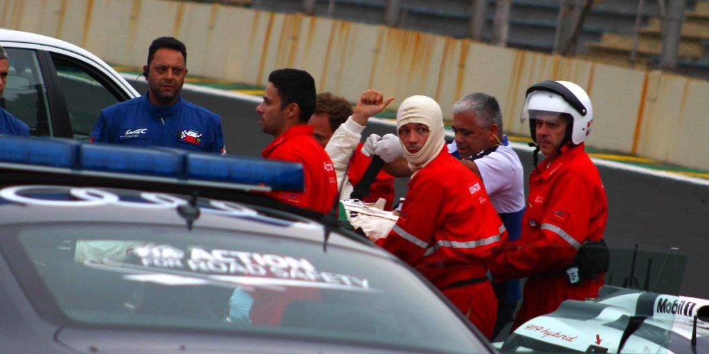 Mark Webber gives a thumbs up as medical team take him from the race track in Sao Paulo.