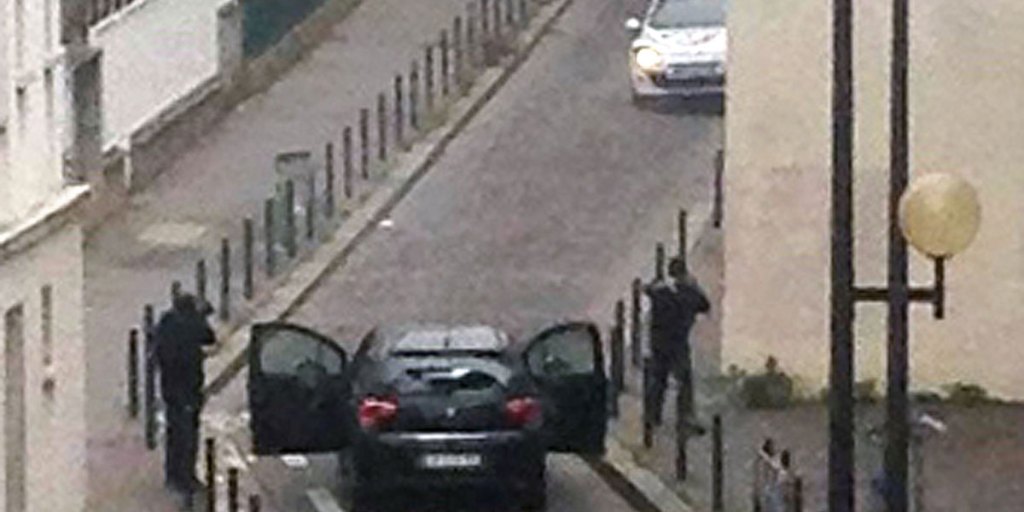 Armed gunmen face police officers near the offices of the French satirical newspaper Charlie Hebdo in Paris.