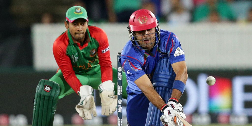 Afghanistan batsman Mohammad Nabi plays a sweep shot as Bangladesh wicketkeeper Mushfiqur Rahim looks on.