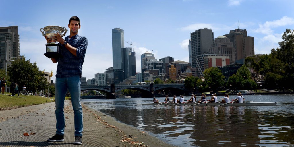 Newly crowned Australian Open champion Novak Djokovic holds the trophy by the Yarra River.