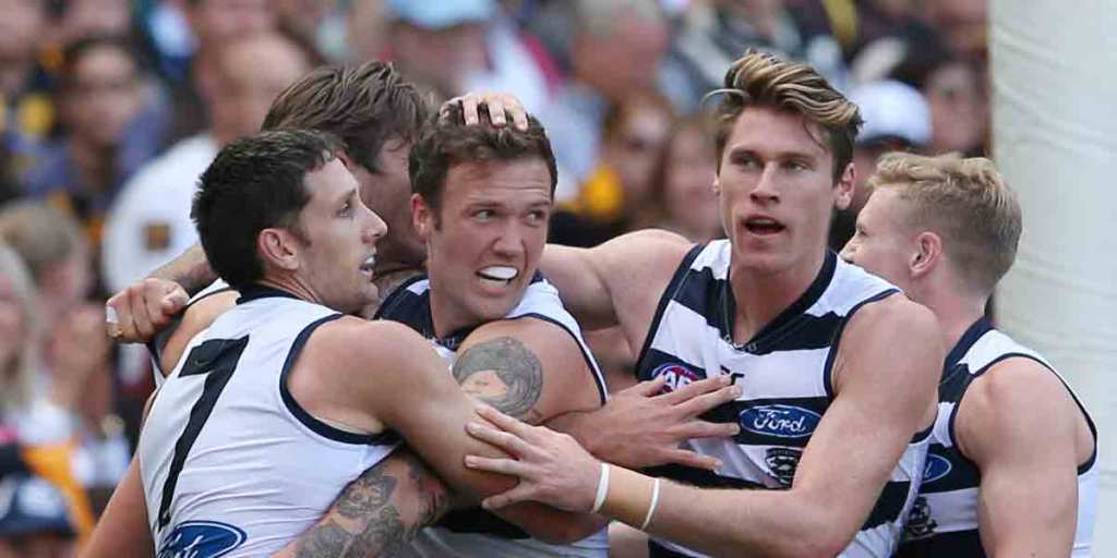 Tattooed Mitch Clark is mobbed by Geelong teammates after scoring for his new team.