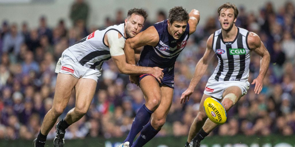 Dockers spearhead Matthew Pavlich chases the ball flanked by Collingwood opponents.