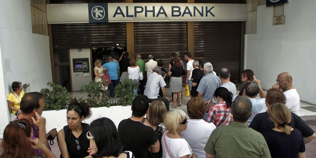 People queue to withdraw money from an ATM at a branch of Greece's Alpha Bank in Athens.