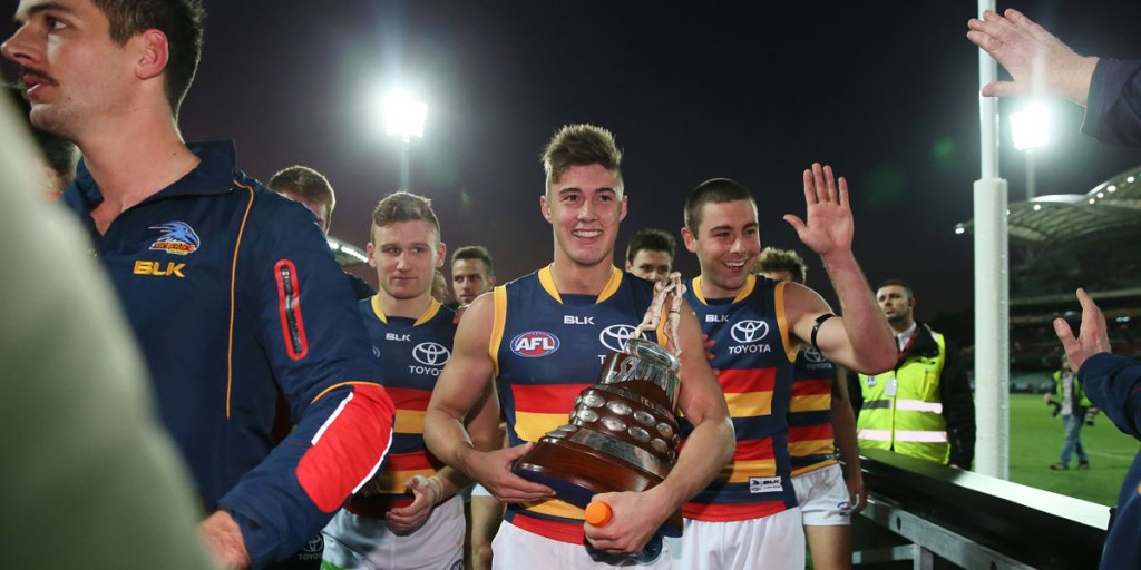 Second-game player Riley Knight leaves Adelaide Oval with the Showdown trophy in his grasp. 
