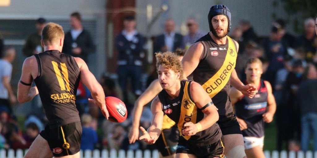 Glenelg's Matt Snook handballs to captain Andrew Bradley, while Warrick McGinty looks on. Photo: Peter Argent
