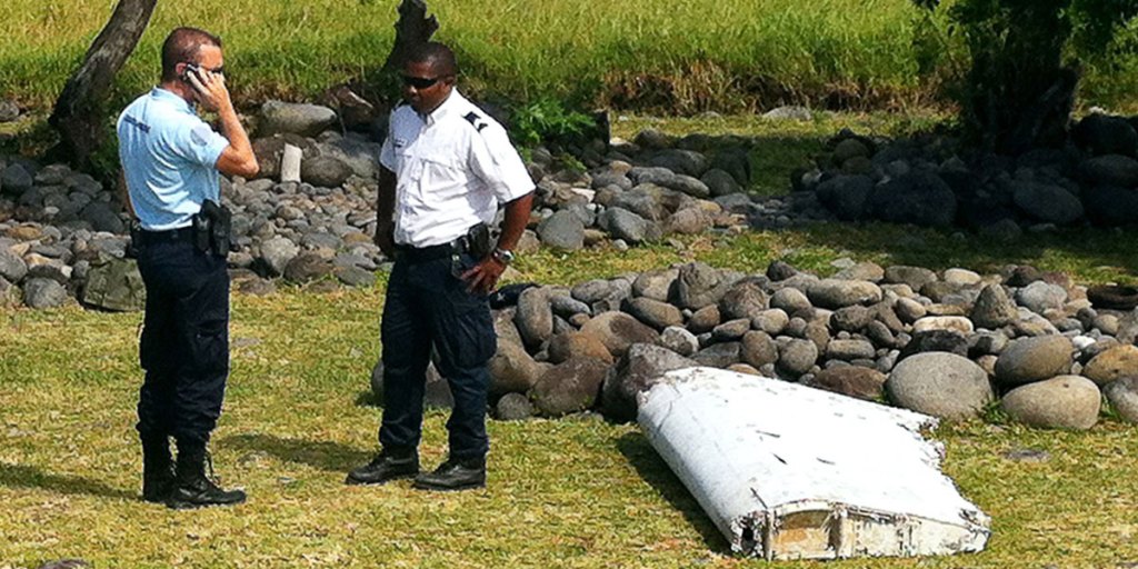 A policeman and a gendarme stand next to a piece of debris from an unidentified aircraft found on the Indian Ocean island of La Reunion. AFP photo