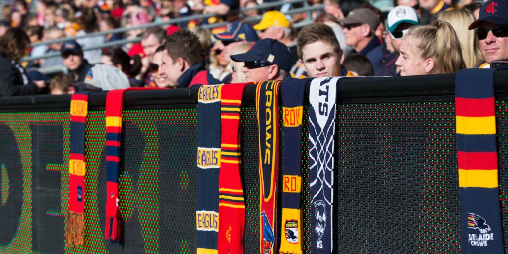 Fans of different clubs hang their scarves on the Adelaide Oval fence during Sunday's tribute to Phil Walsh. AAP image