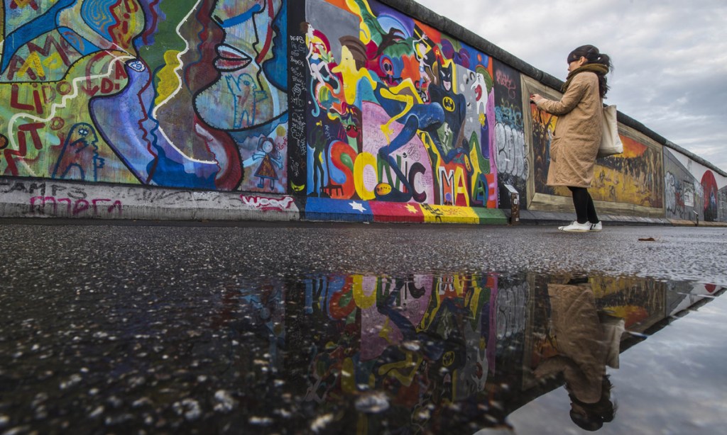 A tourist photographs art on the Berlin Wall. Berlin is considered a 'post-tourism' hot spot.