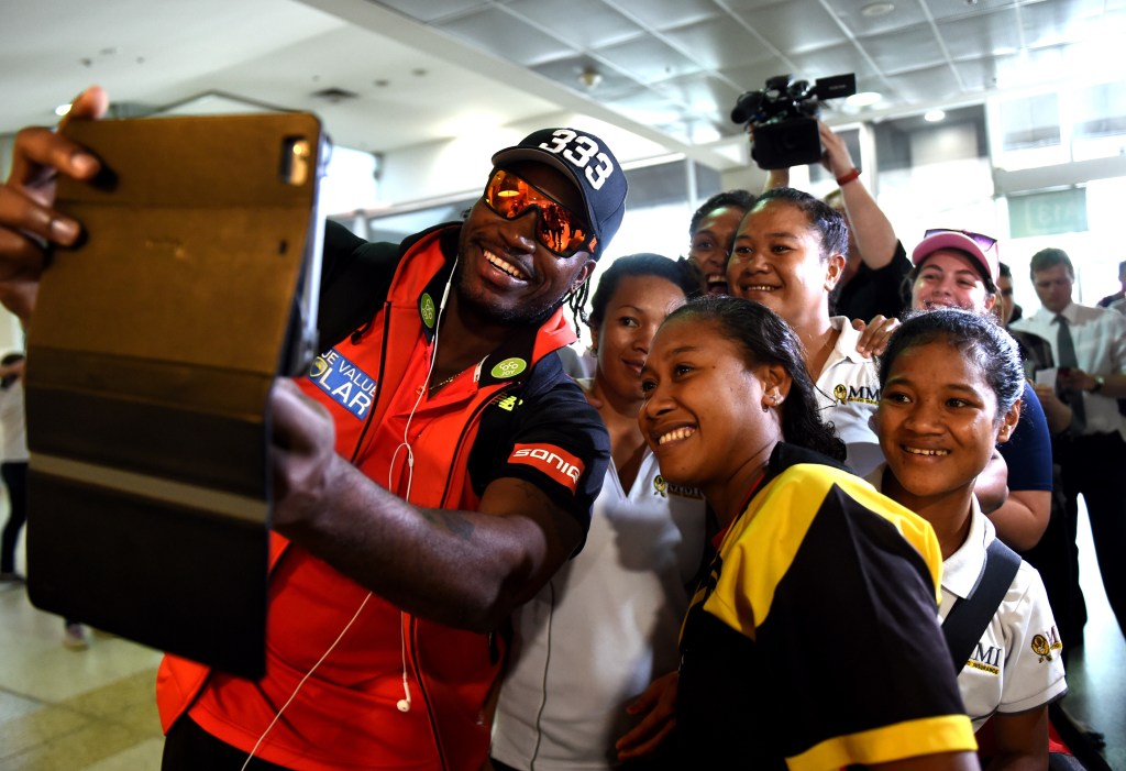 Gayle posed for photographs with the PNG Womens Cricket Team as he arrived at Melbourne Airport ahead of his media conference apology. Photo: Tracey Nearmy, AAP.