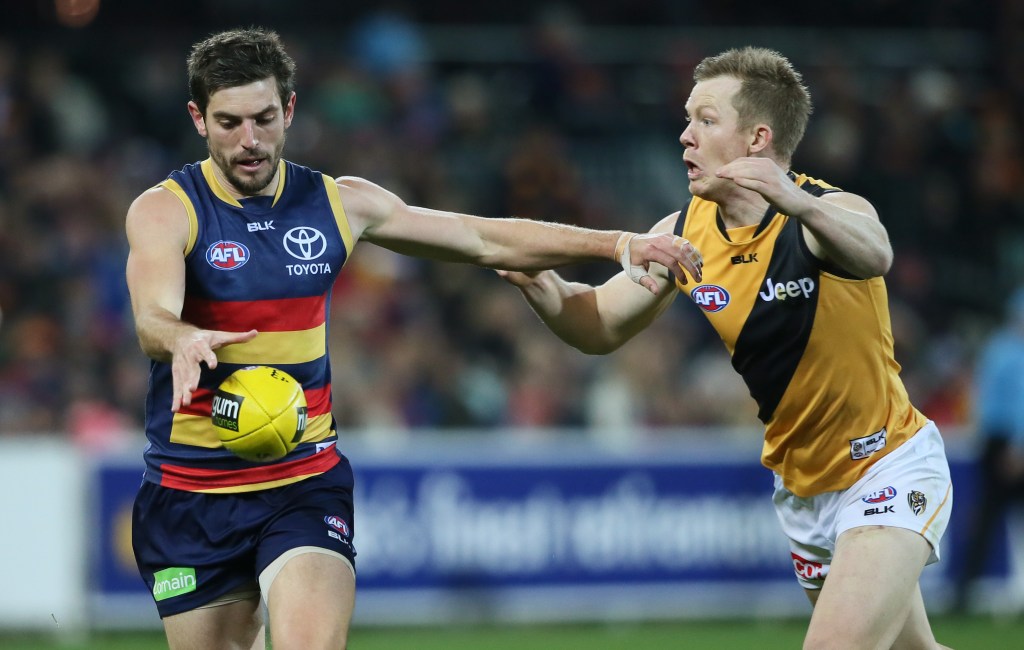 Ricky Henderson gets a kick away under pressure from Tiger Jack Riewoldt. Photo: Ben Macmahon, AAP.
