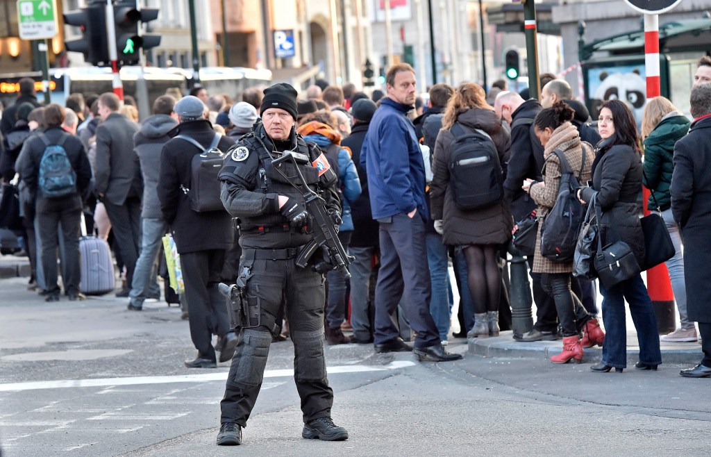 People queue for buses behind a policeman in Brussels. Photo: AP/Martin Meissner)