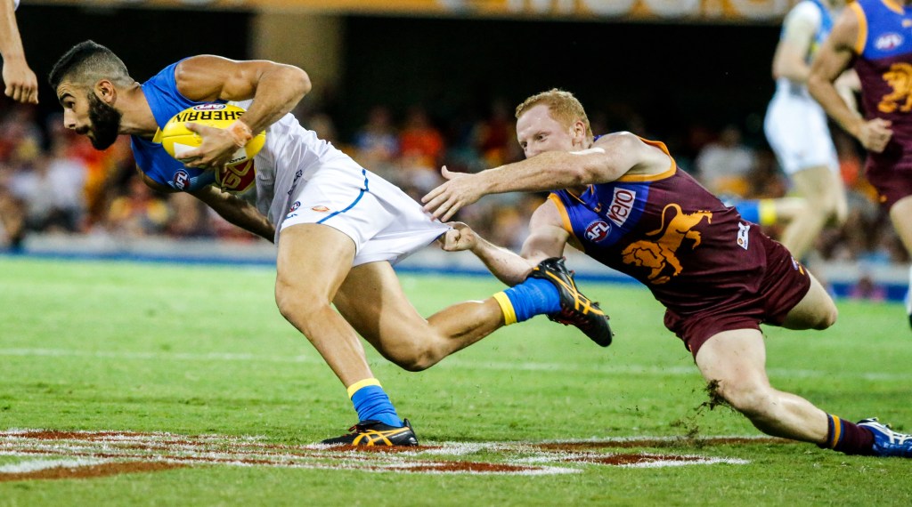ONLY ROOM FOR ONE TEAM IN QUEENSLAND? Adam Saad of the Suns is tackled by Brisbane's Josh Green. Photo: Glenn Hunt, AAP.