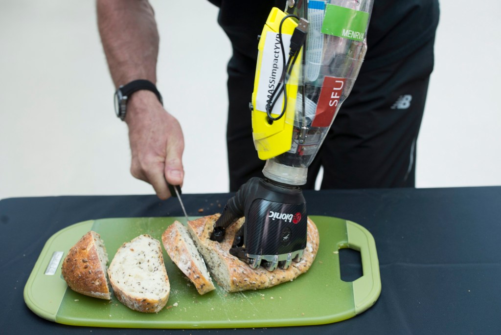 Danny Letain, who lost his hand in an accident 25 years ago, uses a bionic hand to help him cut bread earlier this month. Photo: Jonathan Hayward/The Canadian Press