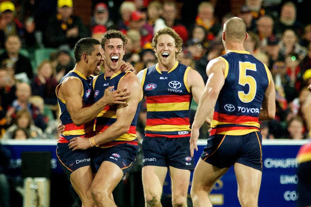 Teammates get around Kyle Hartigan after the defender scored his first AFL goal against Essendon. Photo: Michael Errey, InDaily.