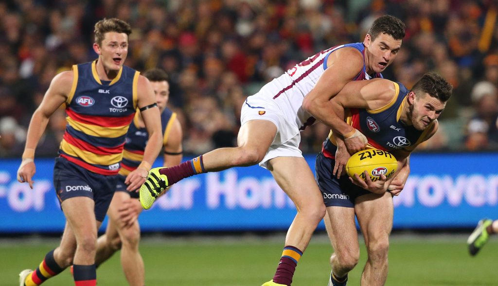 Brad Crouch attempts to break a tackle from Tom Rockliff during the match between the Adelaide Crows and the Brisbane Lions at Adelaide Oval on August 6. Photo: AAP
