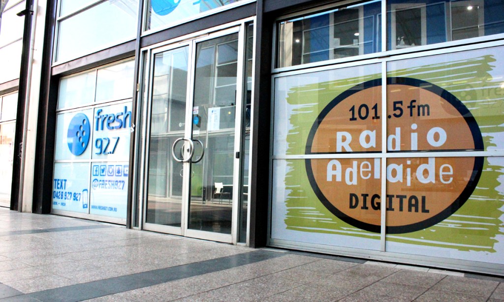 Radio Adelaide's branding seen in the window of its city studios. Photo: Jordan Patrick/InDaily.