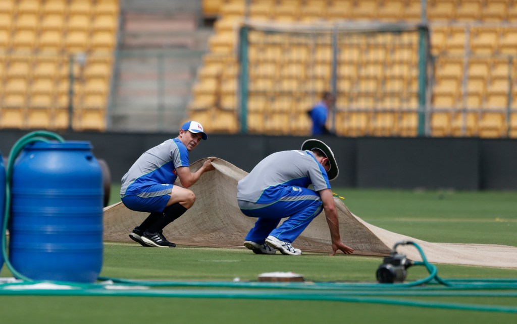 Australia's Steve O'Keefe (left) and Mitchell Marsh lift a cloth to check the pitch area before a training session this week. Photo: Aijaz Rahi / AP