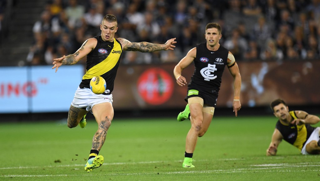 Dustin Martin gets a kick away in front of Blues skipper Marc Murphy. Photo: Julian Smith / AAP