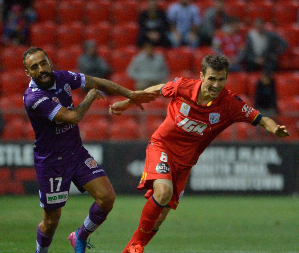 Perth's Diego Castro tussles with Adelaide's Isaias Sanchez during Friday's match. Photo: AAP/David Mariuz