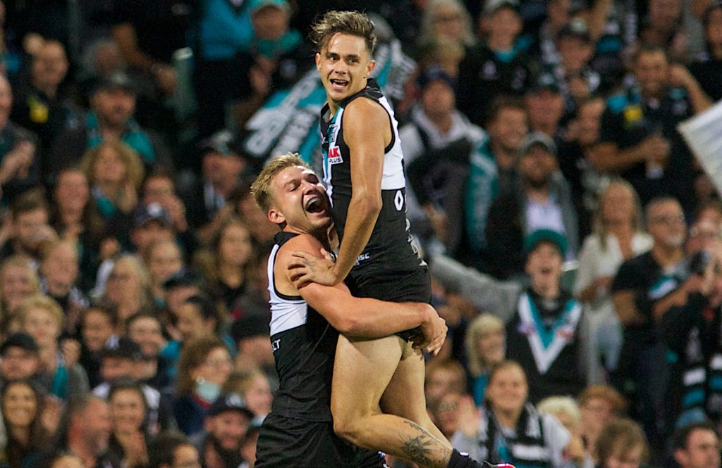 Ollie Wines embraces Aidyn Johnson after his first kick in the AFL results in a goal. Photo: Michael Errey / InDaily