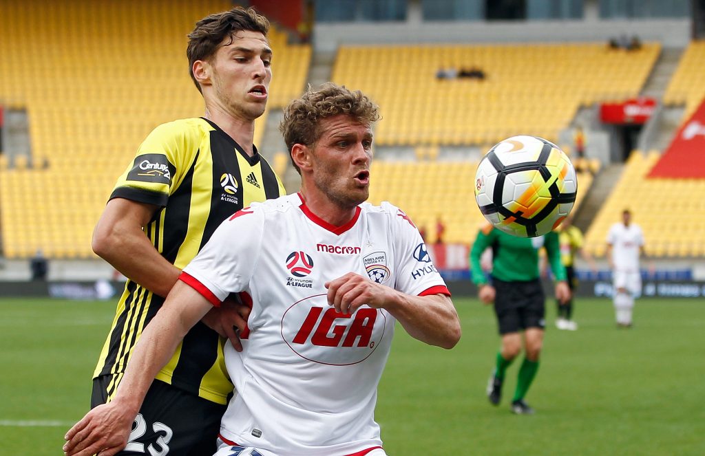 Johan Absalonsen of Adelaide (right) keeps his eye on the ball as he keeps Matthew Ridenton of the Phoenix at bay. Photo: AAP/SNPA/Dean Pemberton