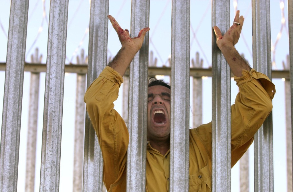 An asylum seeker, bloodied by razor wire, cries out moments before a breakout from the Woomera Detention Centre 2002. Photo: AP/Rick Rycroft