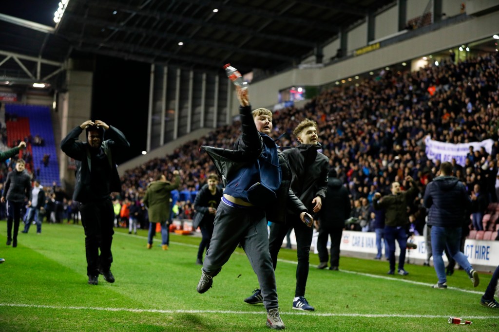 Fans invade the pitch after Wigan defeated Manchester city at the DW Stadium, Wigan. Photo: Lynne Cameron/Sportimage via PA Images.