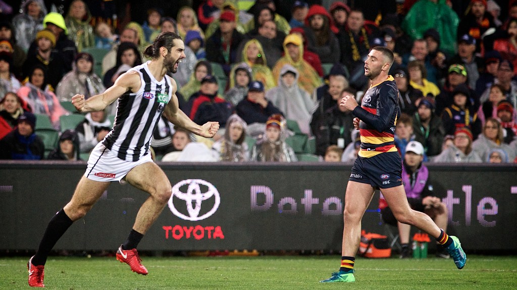 Brodie Grundy celebrates a goal while Rory Atkins ponders the dubious retro appeal of the long-sleeved guernsey. Photo: Michael Errey / InDaily