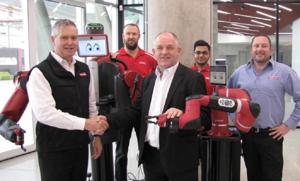 REDARC founder Anthony Kittel, left, shakes hands with the Chair of Information Technology at Flinders, Professor John Roddick, alongside one of the smart robots that his firm co-purchased for use by science and engineering students.