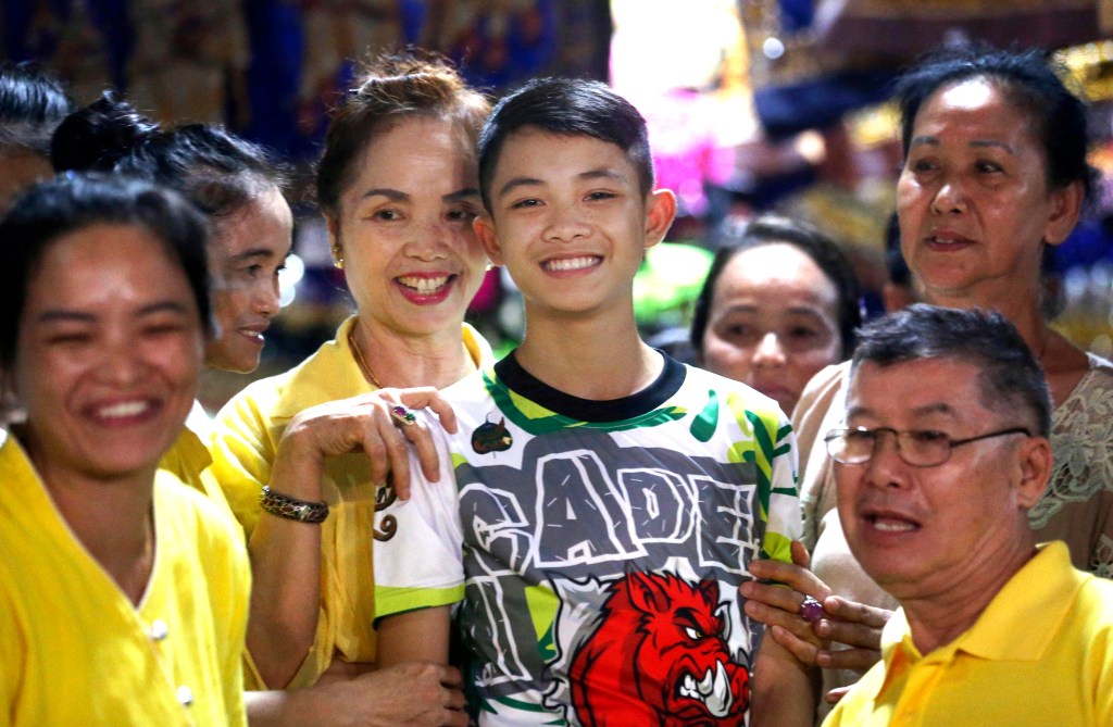 Duangpetch Promthep, one of the boys rescued from a flooded cave, is greeted by relatives at his home in Mae Sai district, Chiang Rai province. Photo: AP/Sakchai Lalit