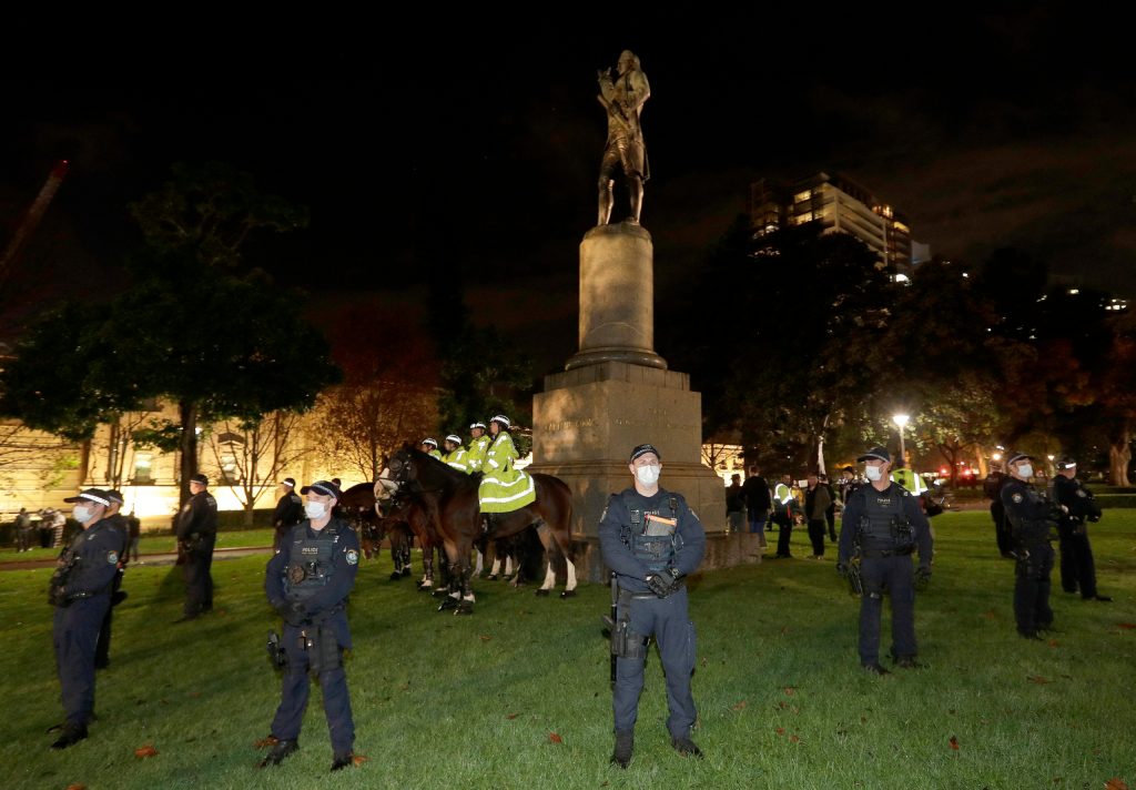 Police guard a statue of British explorer James Cook as protesters gather in Sydney. Photo: AP/Rick Rycroft
