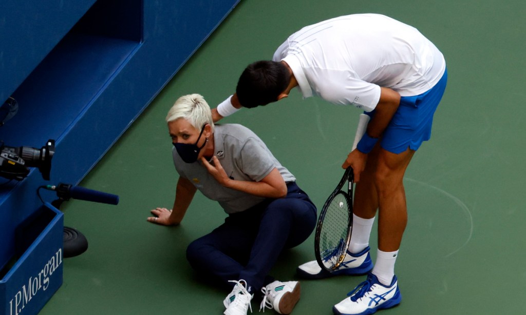 Novak Djokovic tries to help a lines judge after hitting her with a ball in the throat during his match against Pablo Carreno Busta. Picture: Jason Szenes/EPA.