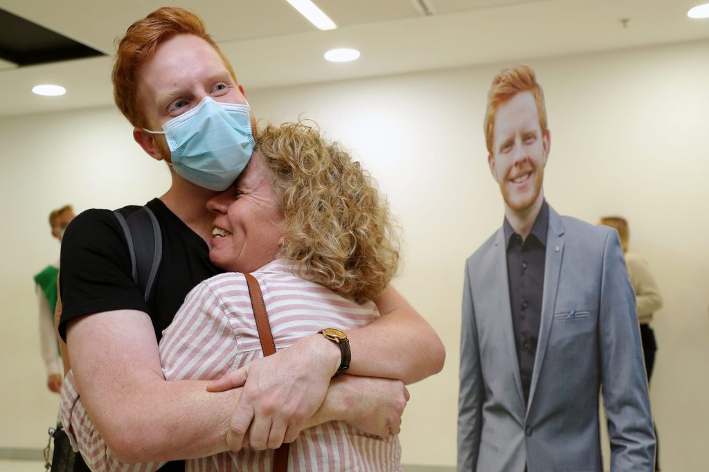 Passengers from Adelaide are greeted by family members after arriving at Perth domestic Airport on Saturday, as the state's hard borders finally come down. Image: AAP Image/Richard Wainwright