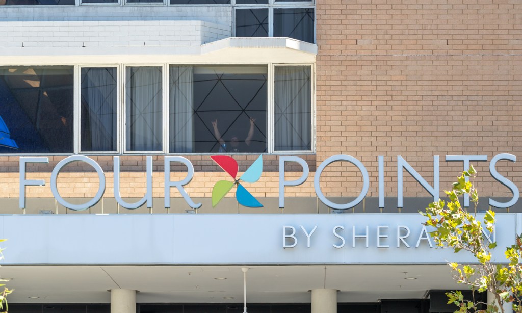 A traveller in quarantine gestures from his window at the Four Points Sheraton hotel where a security guard worked and tested positive for COVID-19 in Perth. Picture: Richard Wainwright/AAP.
