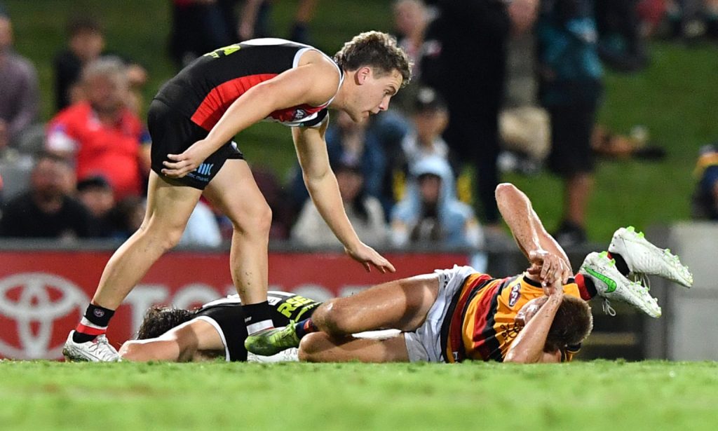 St Kilda's Jack Lonie checks on injured team mate Hunter Clark (centre) and David Mackay after their collision. Photo: AAP/Darren England