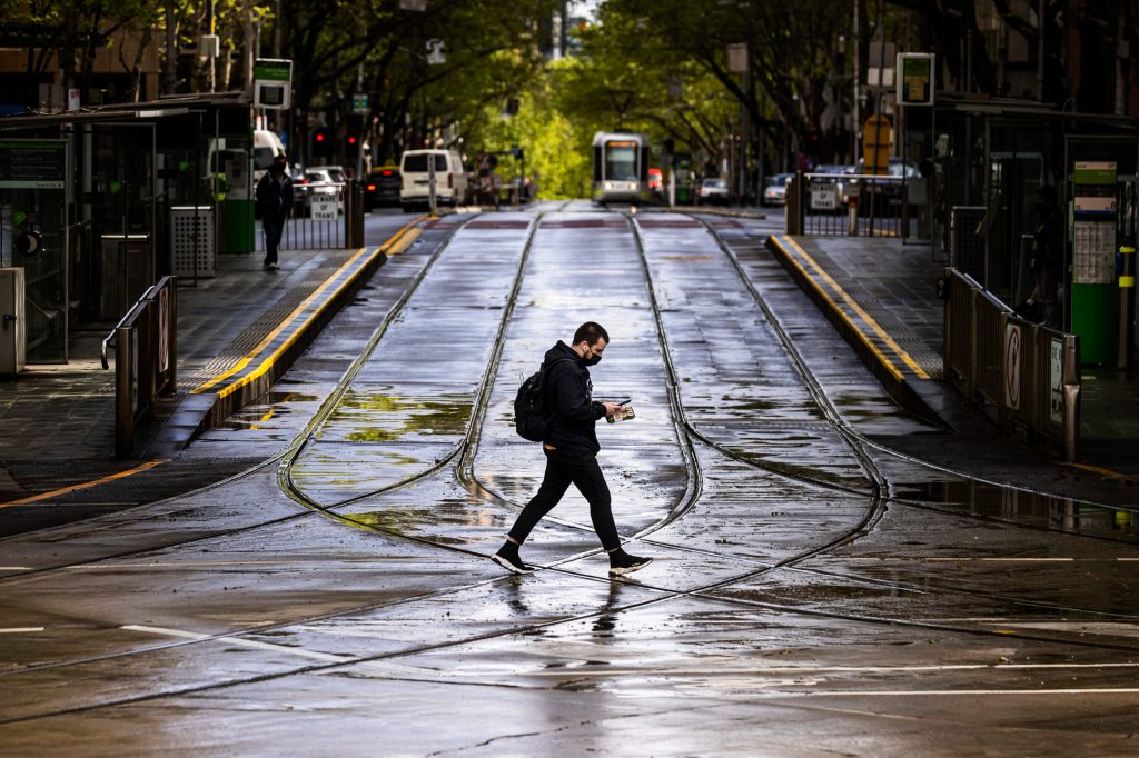 A lone person is seen crossing Collins Street in Melbourne, Monday, October 4, 2021 (AAP Image/Daniel Pockett).