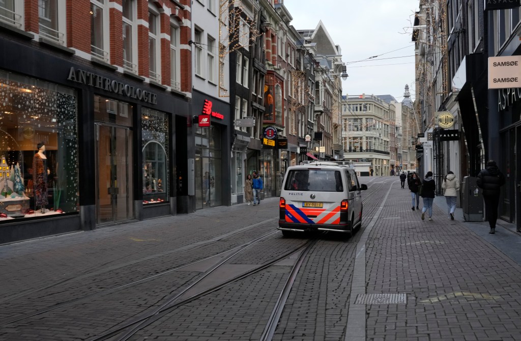 Police patrol an near-empty street in the centre of Amsterdam. All non-essential stores are closed until mid-January. Photo: AP/Peter Dejong