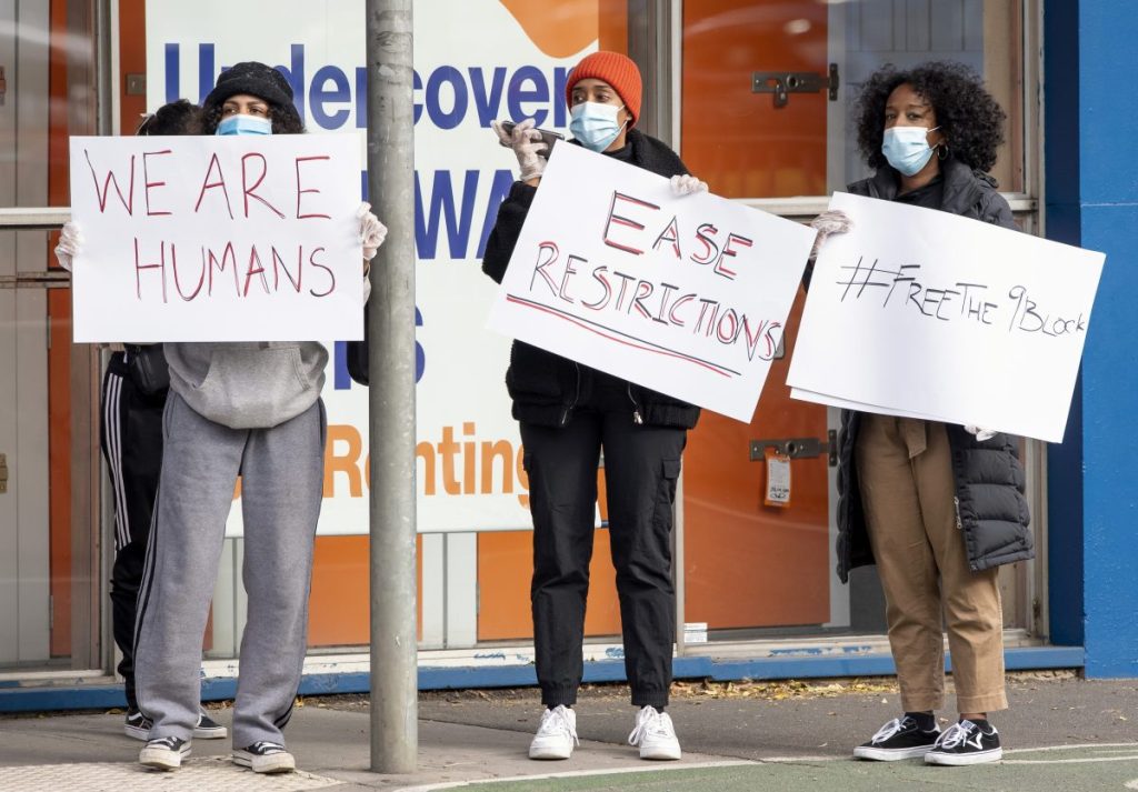 Women hold signs outside housing commission apartments during one of Melbourne's lockdown in 2020. Photo: AP/Andy Brownbill
